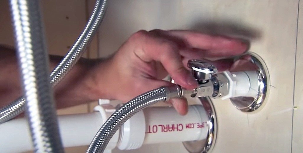 A person fixing a faucet with a hose.