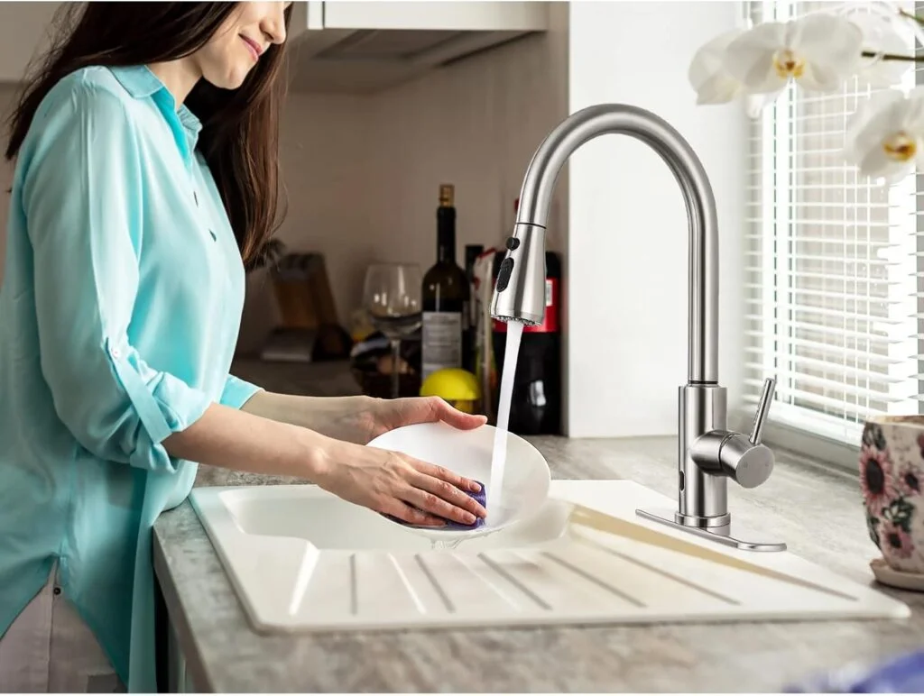 Woman washing dishes in kitchen sink.