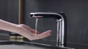 A hand reaches for a faucet in a kitchen sink, ready to activate the water flow